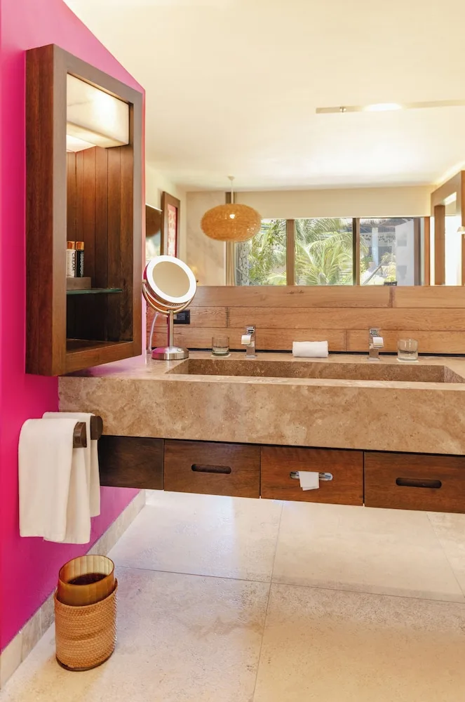 Suite Garden bathroom vanity with stone sink and pink accent wall at Hotel Xcaret Mexico.