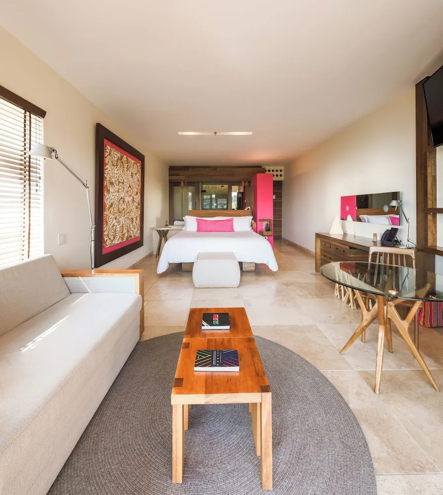 Suite Garden guest room with one bed, sofa, desk and glass table at Hotel Xcaret Mexico.