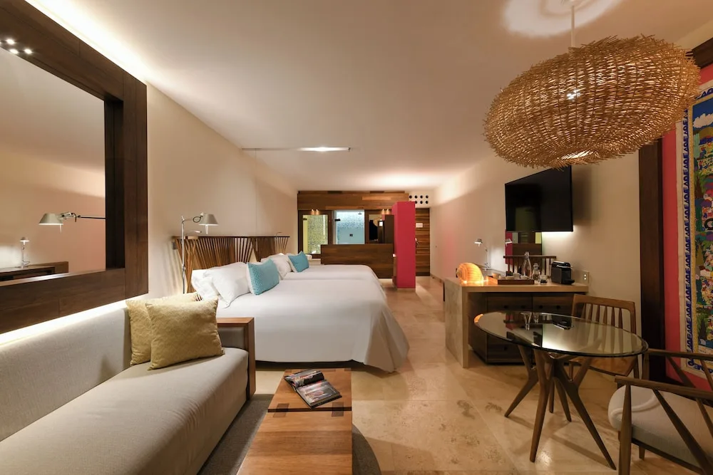 Suite Garden guest room with two beds, sofa and dining table at Hotel Xcaret Mexico.