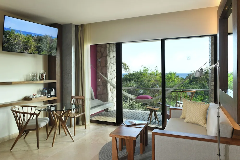 Suite Ocean View sitting area at Hotel Xcaret Mexico with sofa, table, balcony hammock, and ocean view.