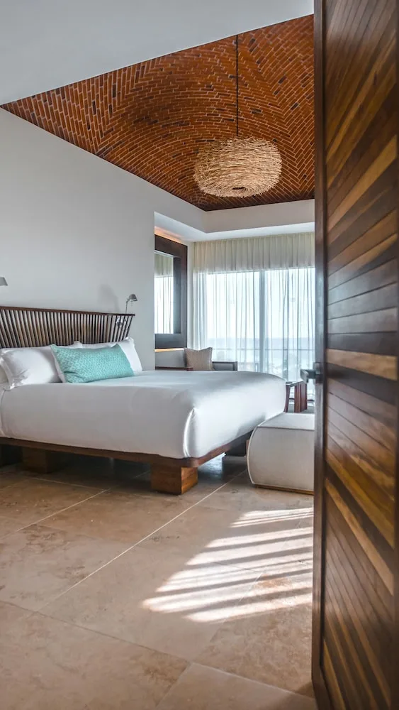 Oceanfront adults-only suite bedroom with king bed and brick ceiling at Hotel Xcaret Mexico.