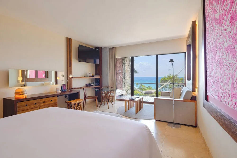 Oceanfront adults-only suite with king bed, sitting area, terrace, and sea view at Hotel Xcaret Mexico.