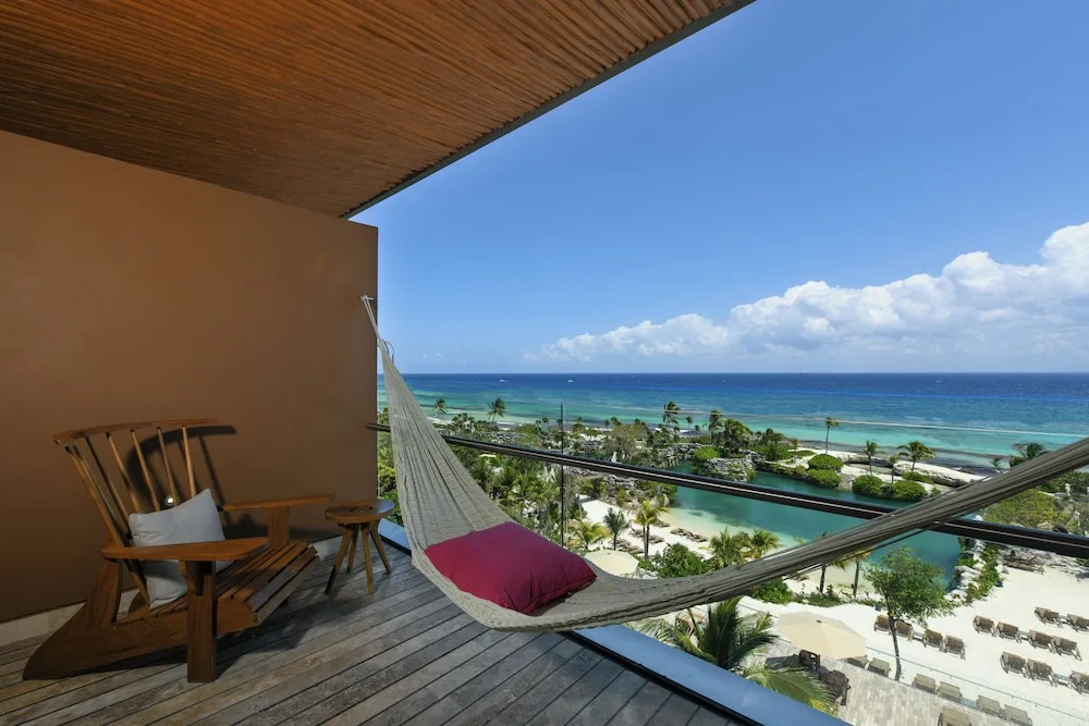 Oceanfront adults-only suite terrace with hammock, chair, and wide sea view at Hotel Xcaret Mexico.