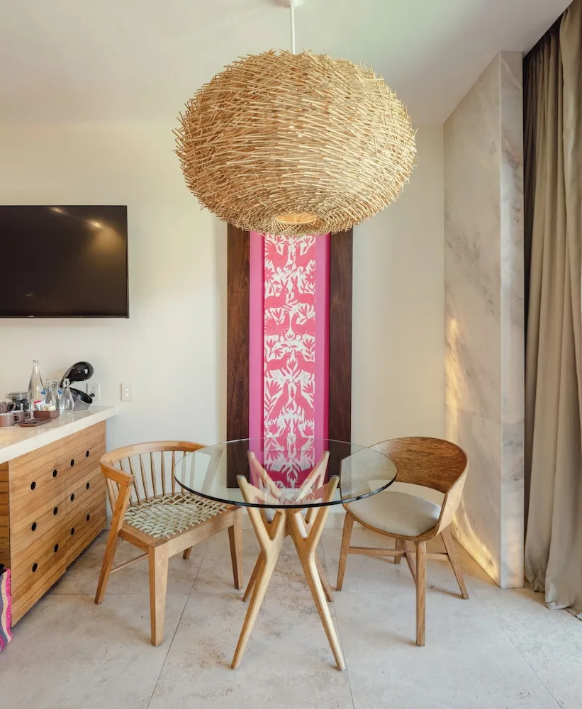 Suite River dining nook with glass table and woven pendant at Hotel Xcaret Mexico.