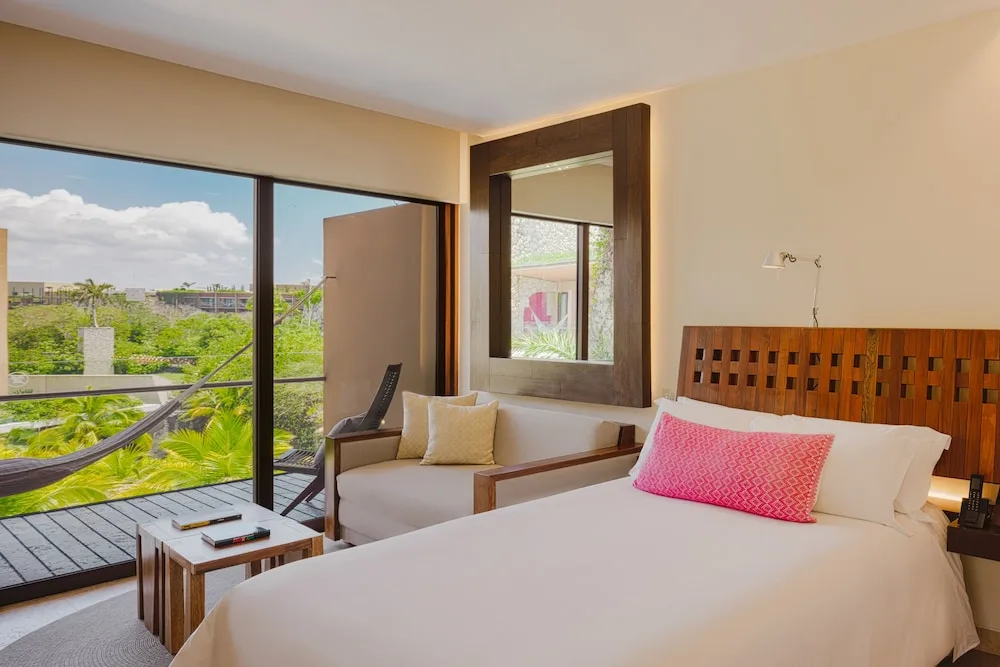 Suite River king bed and balcony view at Hotel Xcaret Mexico.