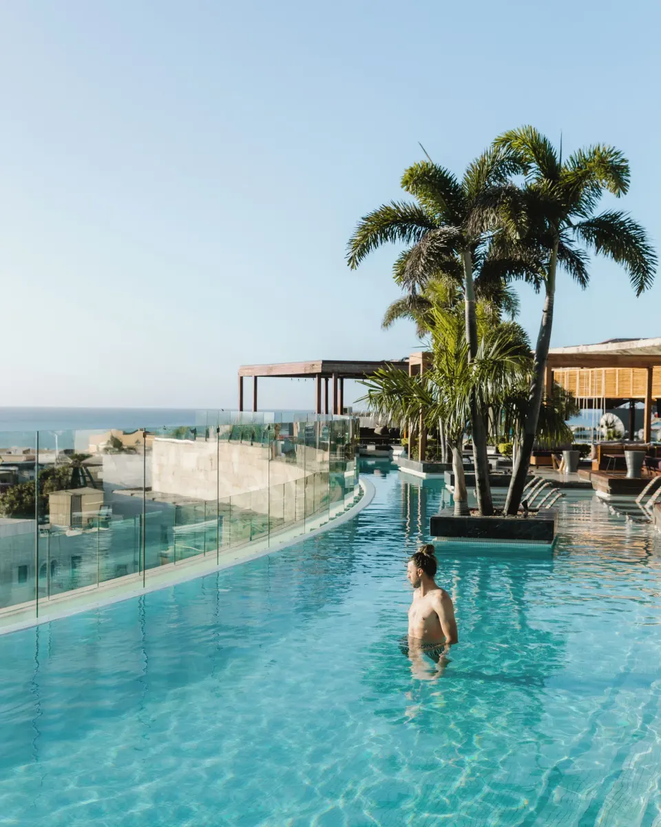 Guest in rooftop pool by glass railing at Hyatt Centric Playa del Carmen - Downtown House & Beach House.