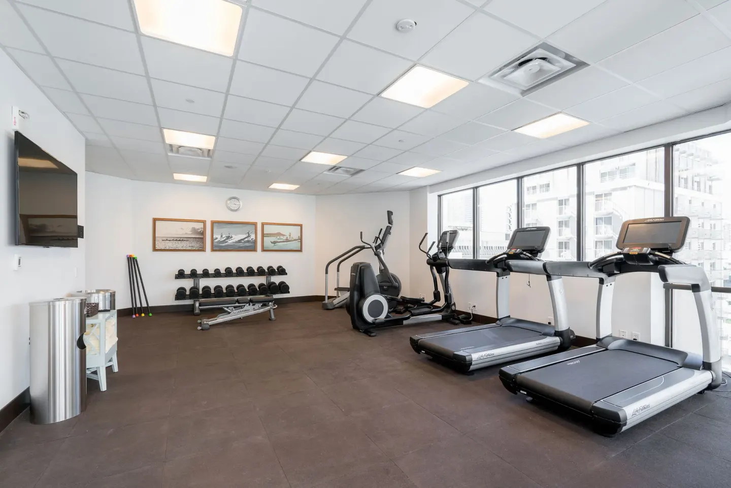 Bright fitness center with treadmills, free weights, and windows at Hyatt Centric Waikiki Beach.