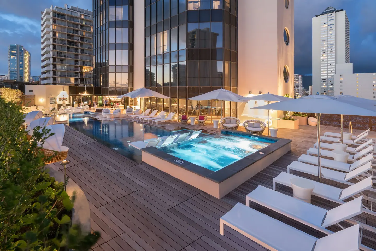 Evening pool terrace with hot tub, loungers and umbrellas at Hyatt Centric Waikiki Beach.