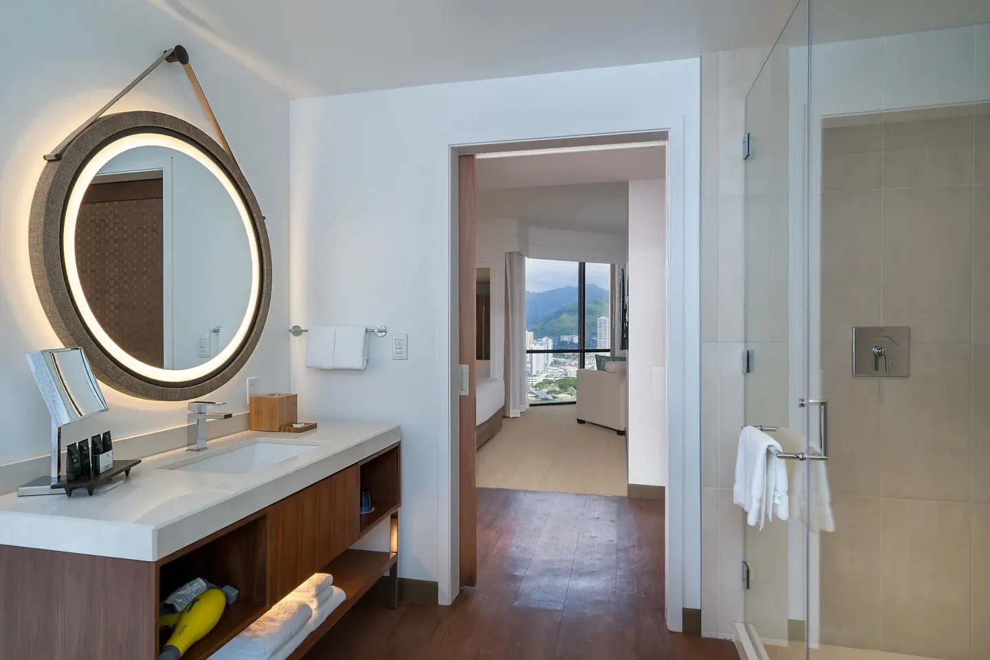 Guest bathroom with vanity, glass shower and bedroom view at Hyatt Centric Waikiki Beach.