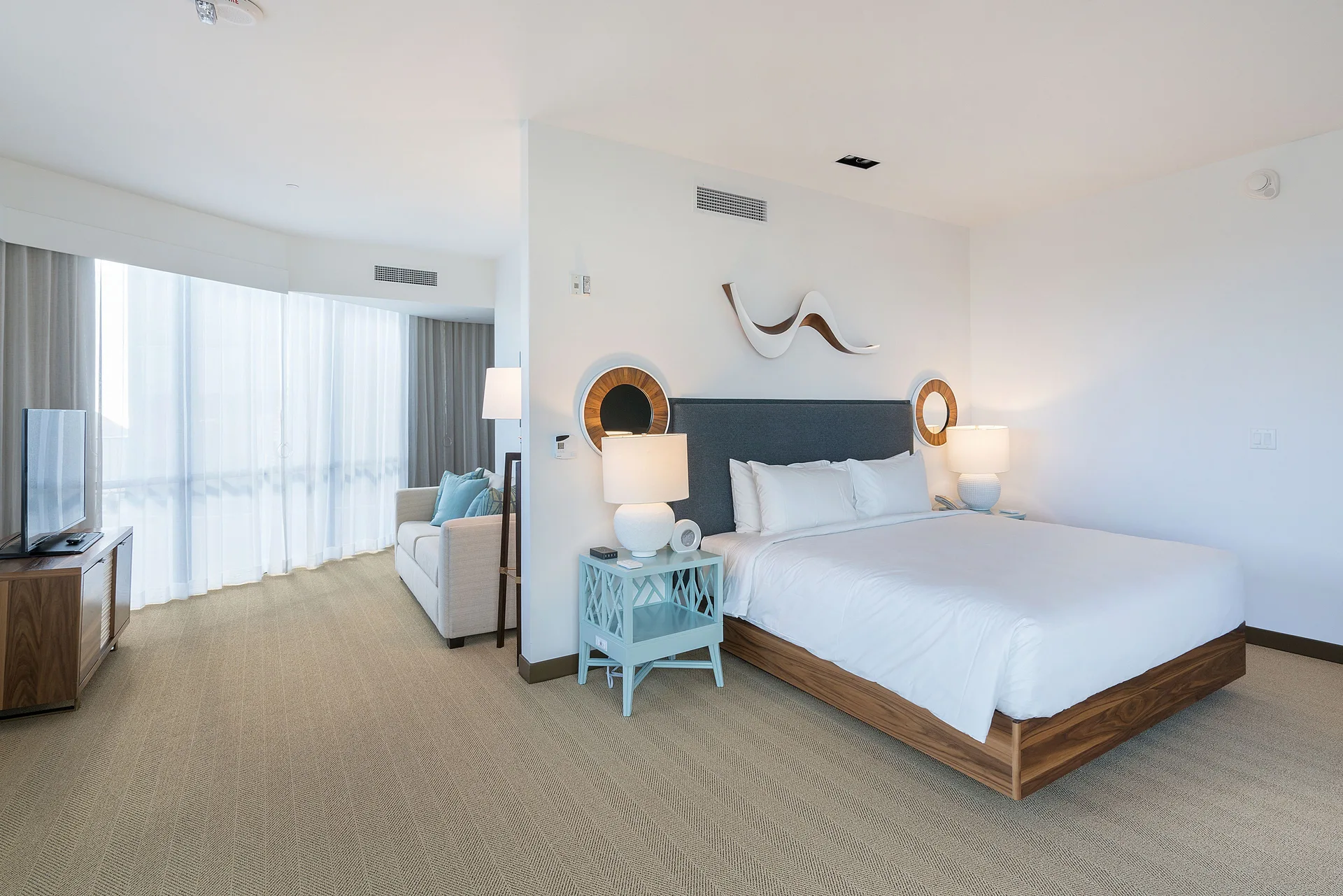 King-bed guest room with sofa and TV at Hyatt Centric Waikiki Beach.