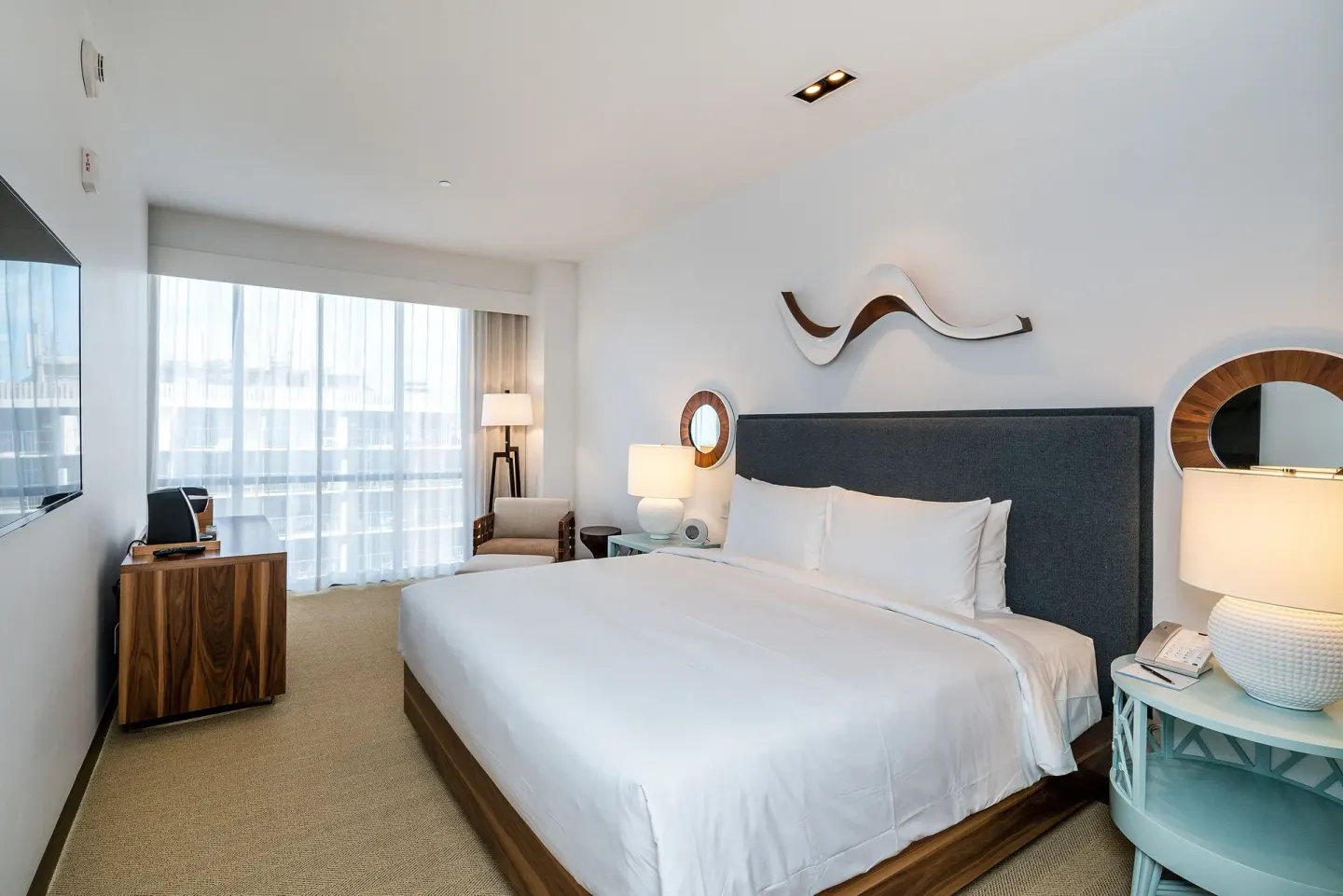 King-bed guest room with TV console and window seating at Hyatt Centric Waikiki Beach.