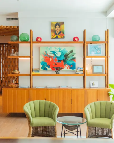 Lobby shelves and green wicker chairs at Hyatt Centric Waikiki Beach with artwork and decor.