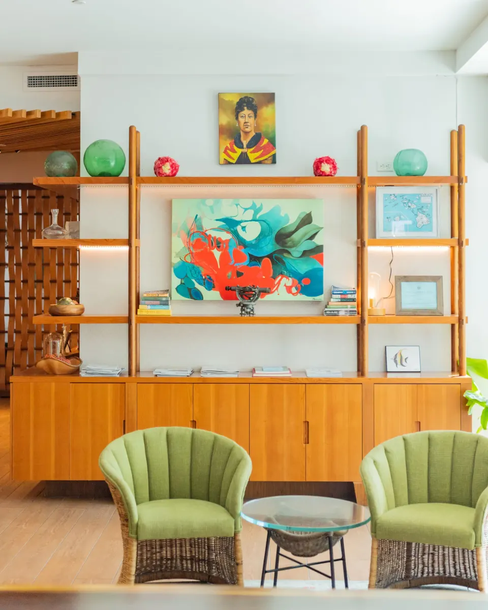 Lobby shelves and green wicker chairs at Hyatt Centric Waikiki Beach with artwork and decor.