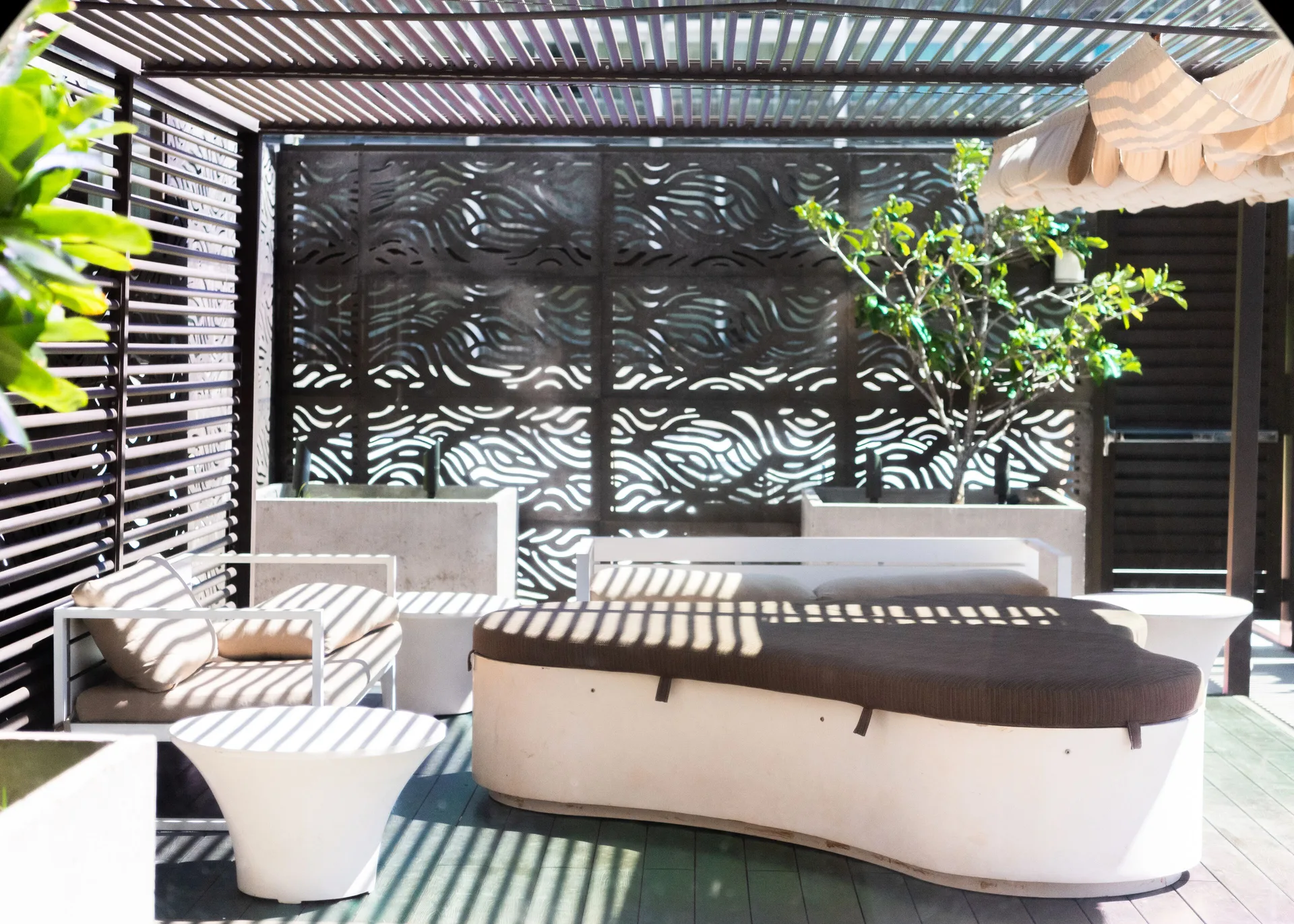 Shaded cabana lounge with patterned screens at Hyatt Centric Waikiki Beach.