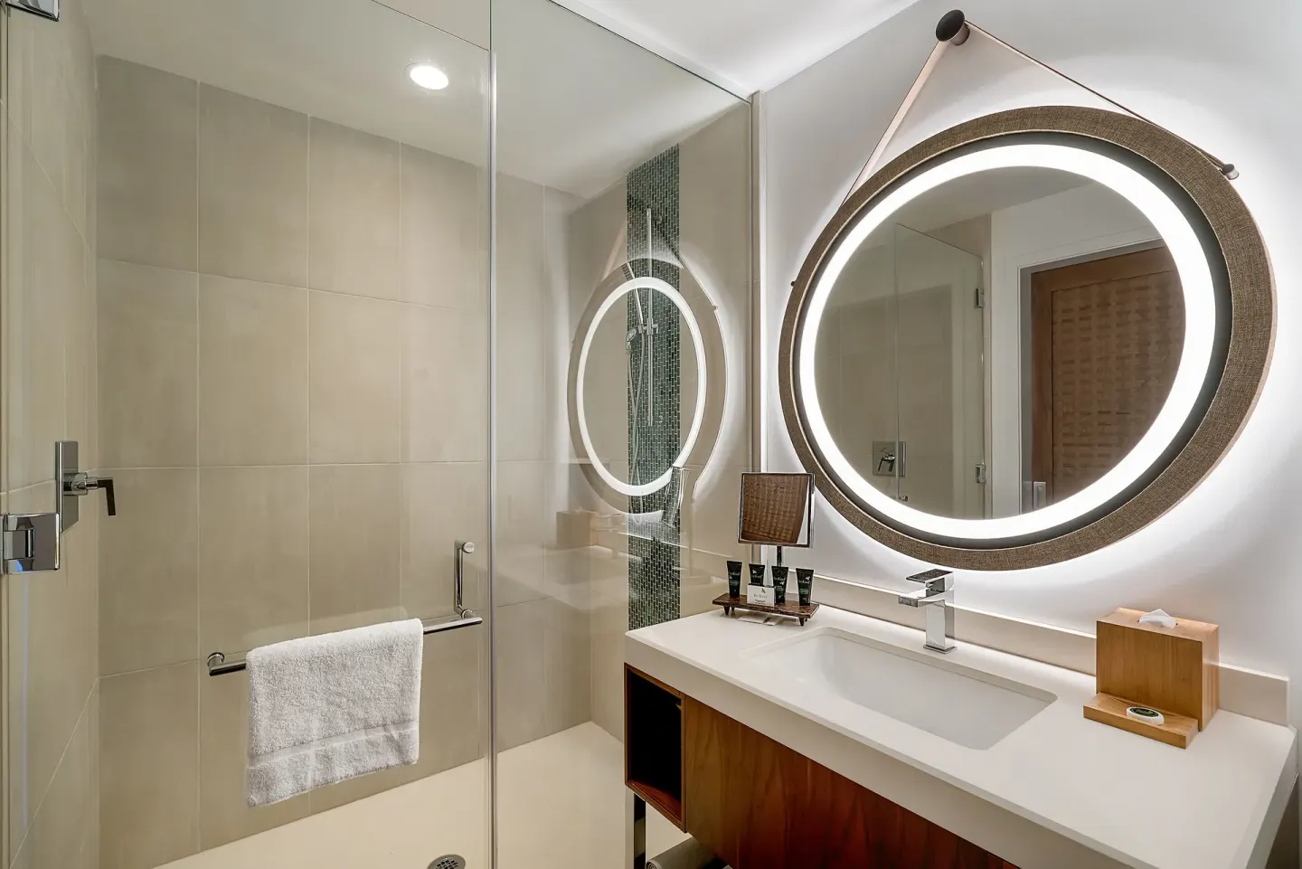 Deluxe room bathroom with glass shower and illuminated mirror at Hyatt Centric Waikiki Beach.