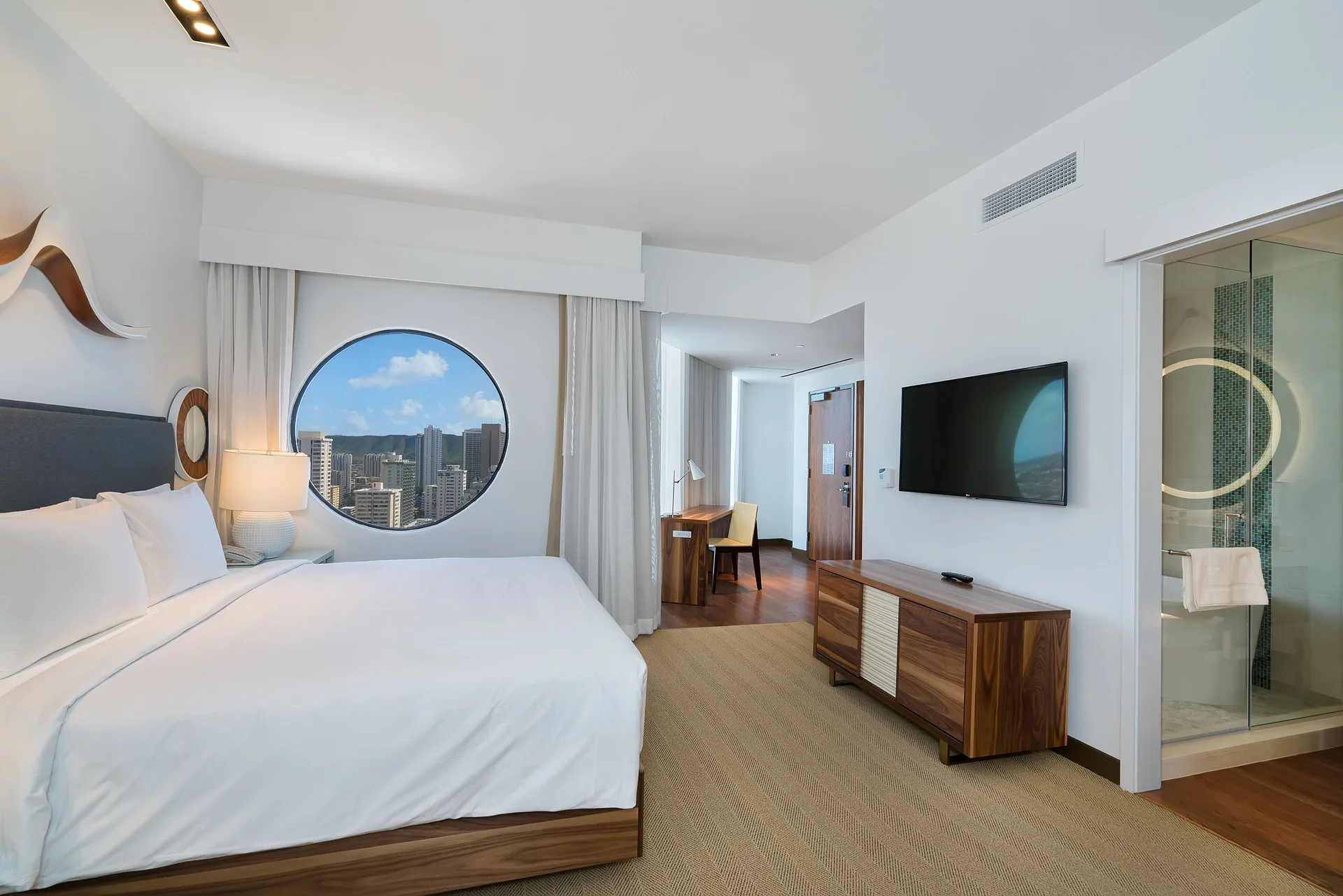 Deluxe king room with circular window and glass shower at Hyatt Centric Waikiki Beach.
