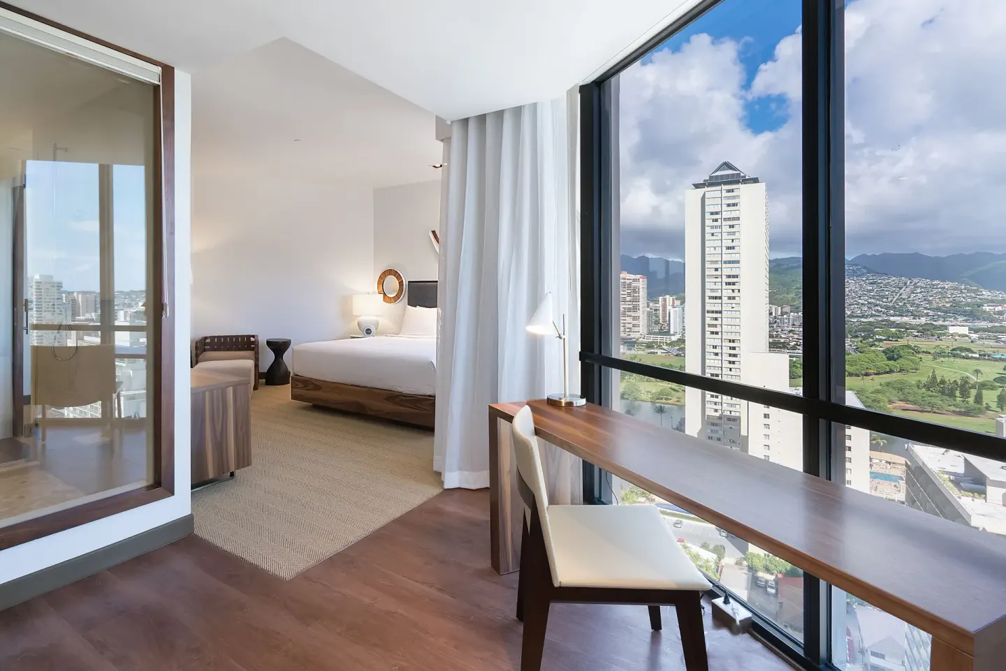 Deluxe room desk and king bed with city views at Hyatt Centric Waikiki Beach.