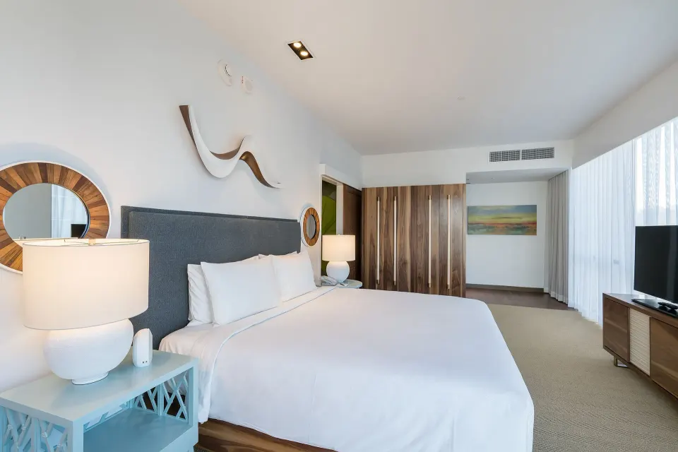 Deluxe king room with bedside lamps, wardrobe, and curtained windows at Hyatt Centric Waikiki Beach.