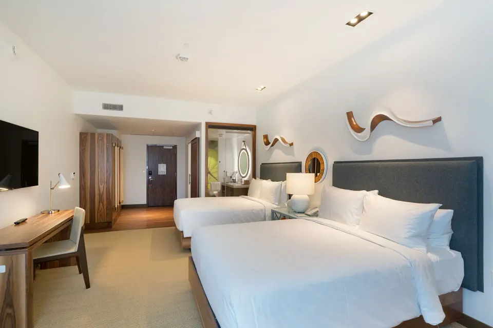 Deluxe room with two beds, desk, wardrobe, and vanity area at Hyatt Centric Waikiki Beach.
