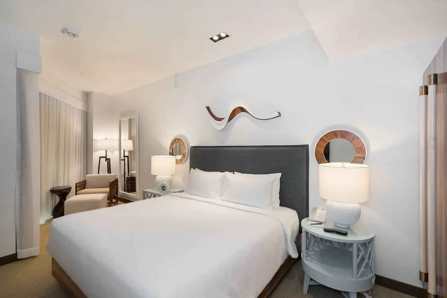High-floor king room with bedside lamps and lounge chair at Hyatt Centric Waikiki Beach.