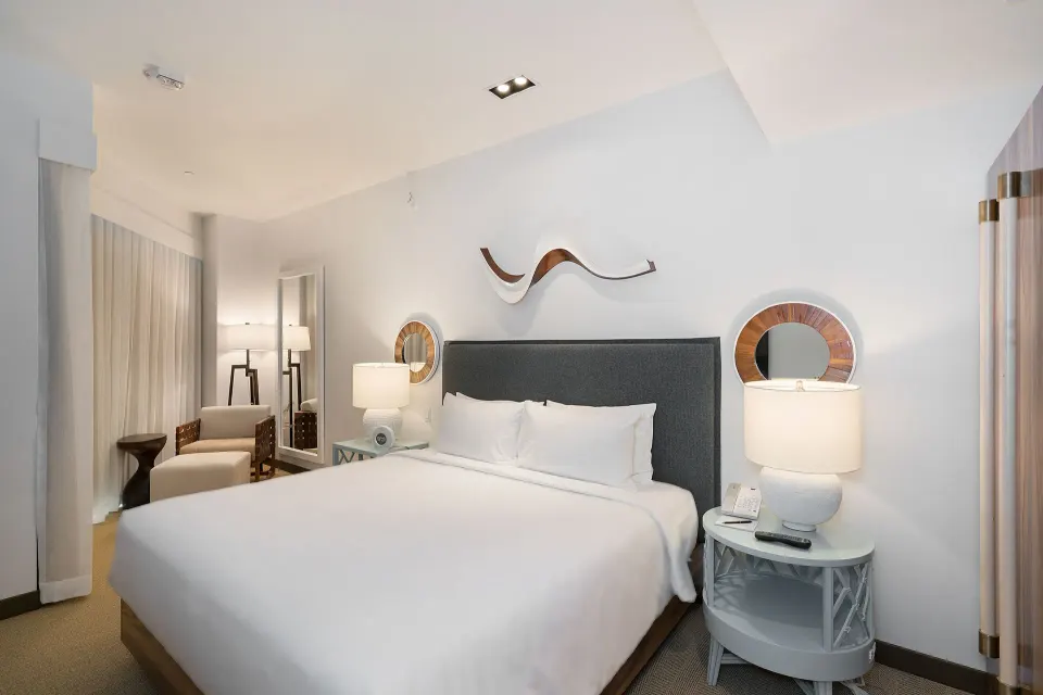 High-floor king room with bedside lamps and lounge chair at Hyatt Centric Waikiki Beach.