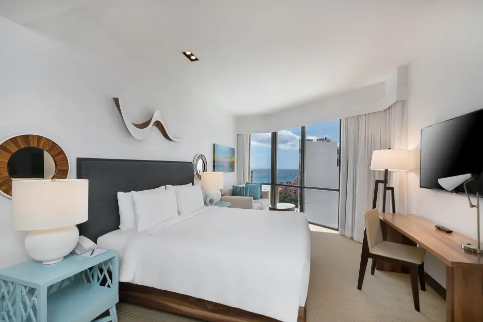 Ocean View room with king bed, desk, seating, and ocean-facing windows at Hyatt Centric Waikiki Beach.