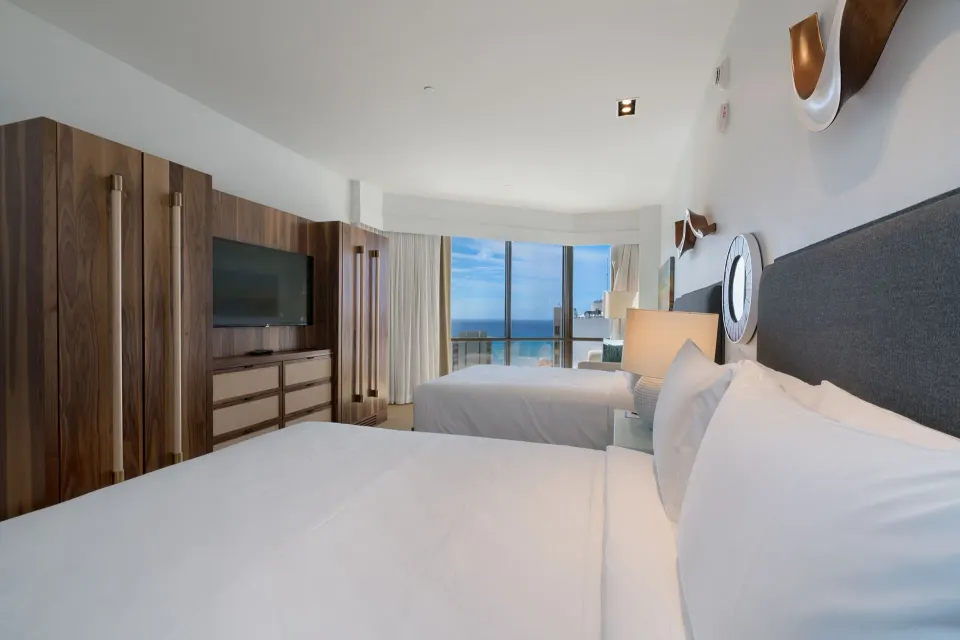 Two-bed ocean view room with TV and large windows at Hyatt Centric Waikiki Beach.