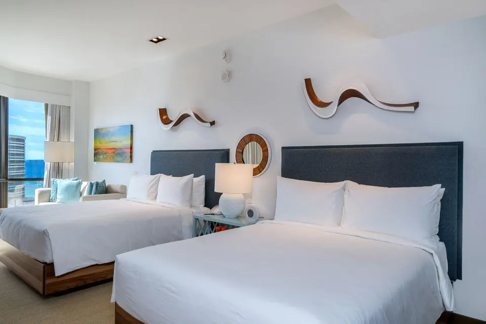 Two white beds beside a window with ocean visible at Hyatt Centric Waikiki Beach.
