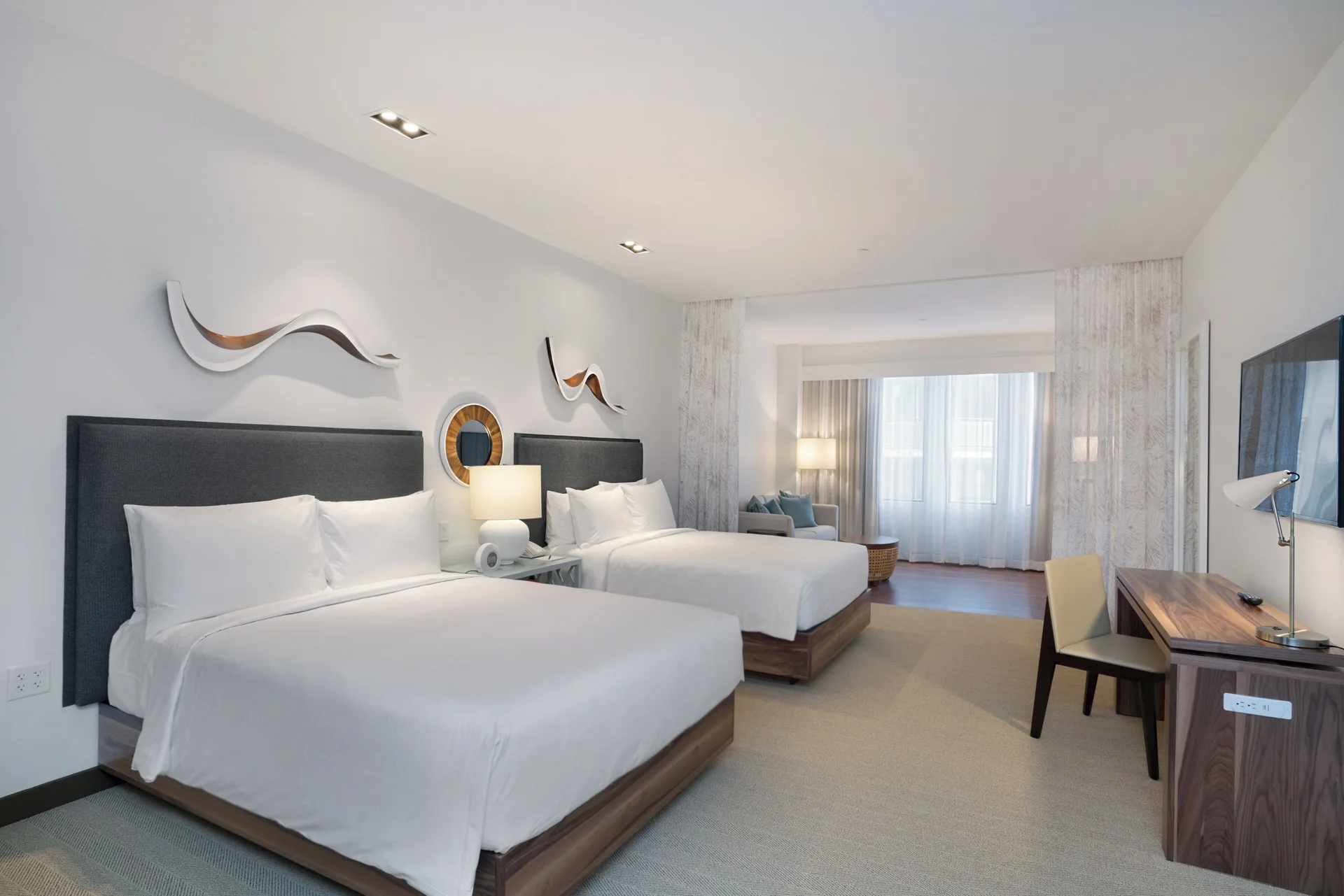 Two-bed suite with desk, artwork, and curtained windows at Hyatt Centric Waikiki Beach.