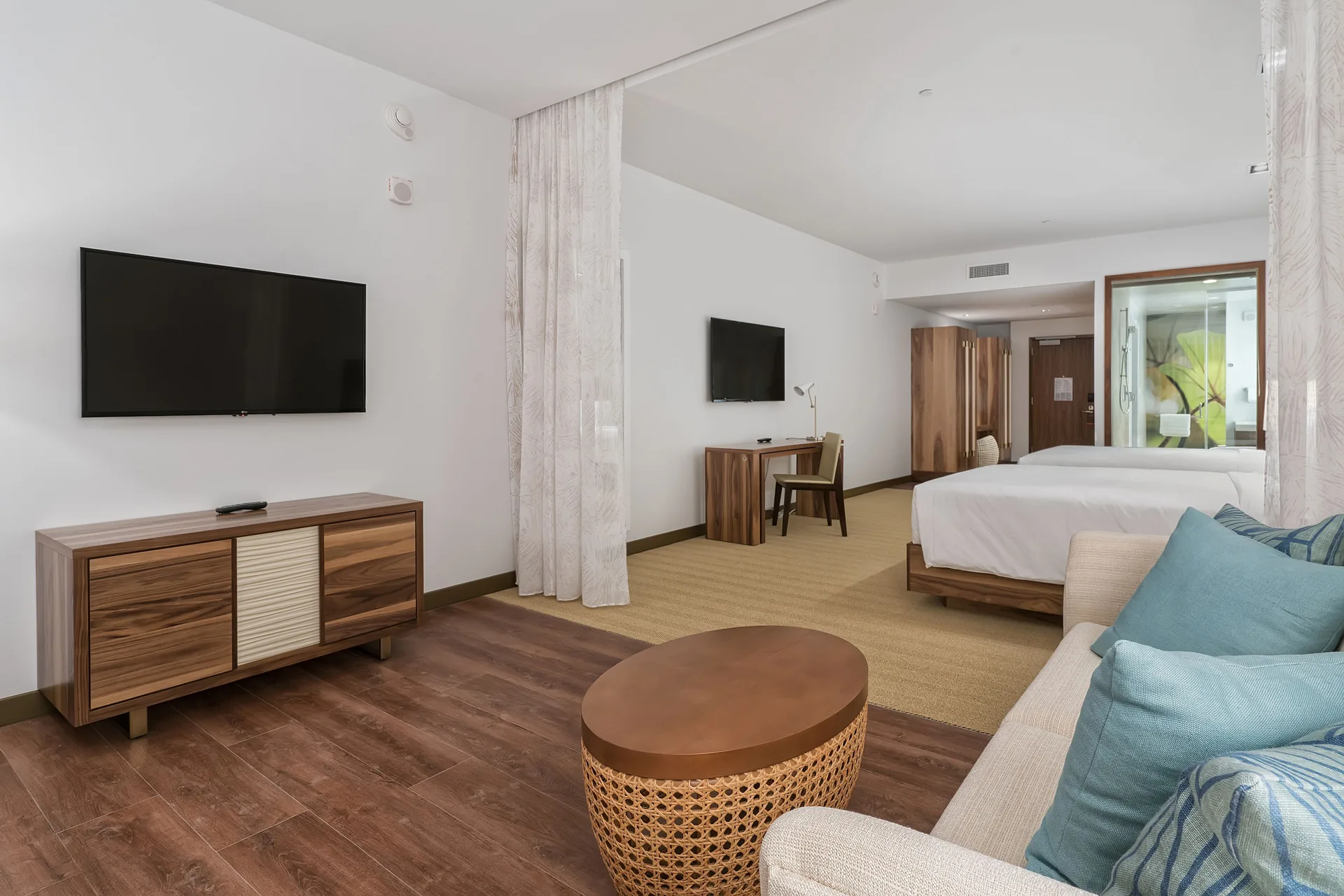 Suite with two beds, sofa seating, and wall-mounted TVs at Hyatt Centric Waikiki Beach.