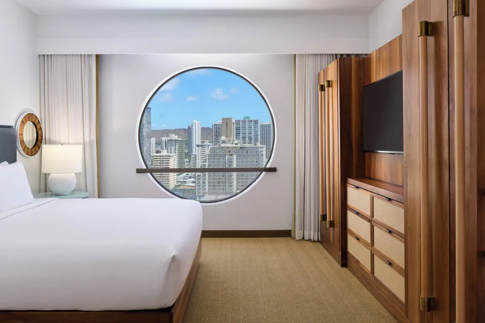 Ocean View Suite king bedroom with round window and TV wall at Hyatt Centric Waikiki Beach.