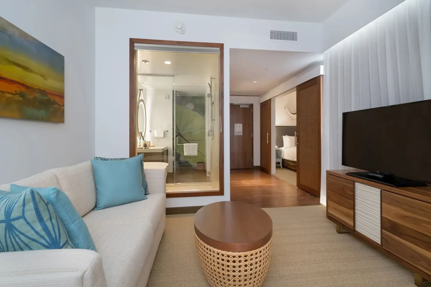 Ocean View Suite living area with sofa, TV, bath and bedroom at Hyatt Centric Waikiki Beach.