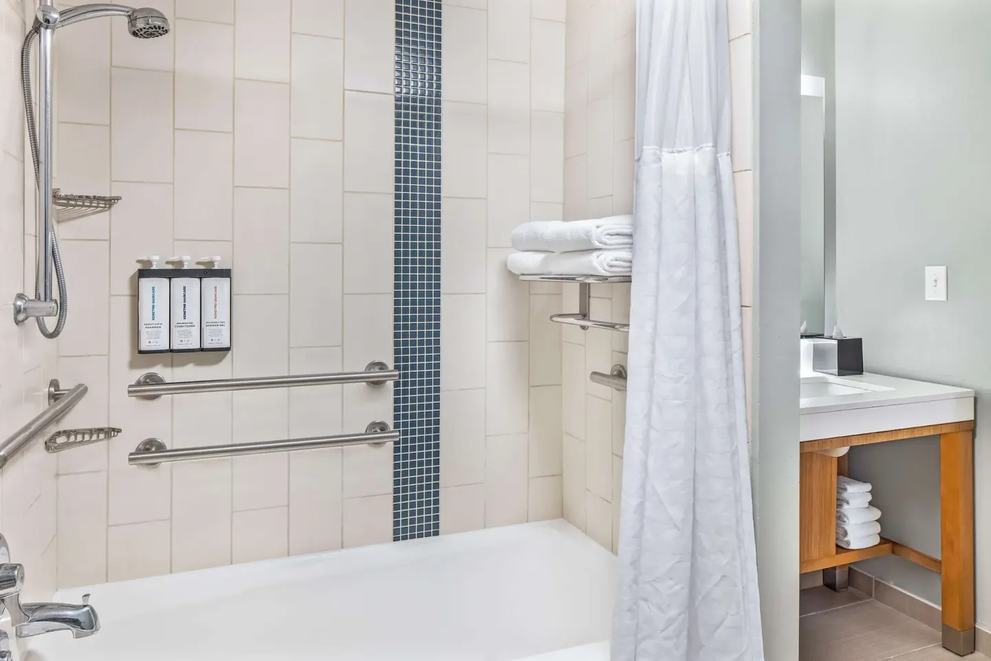 Accessible bathroom with tub, grab bars, and vanity at Hyatt Place Waikiki Beach.