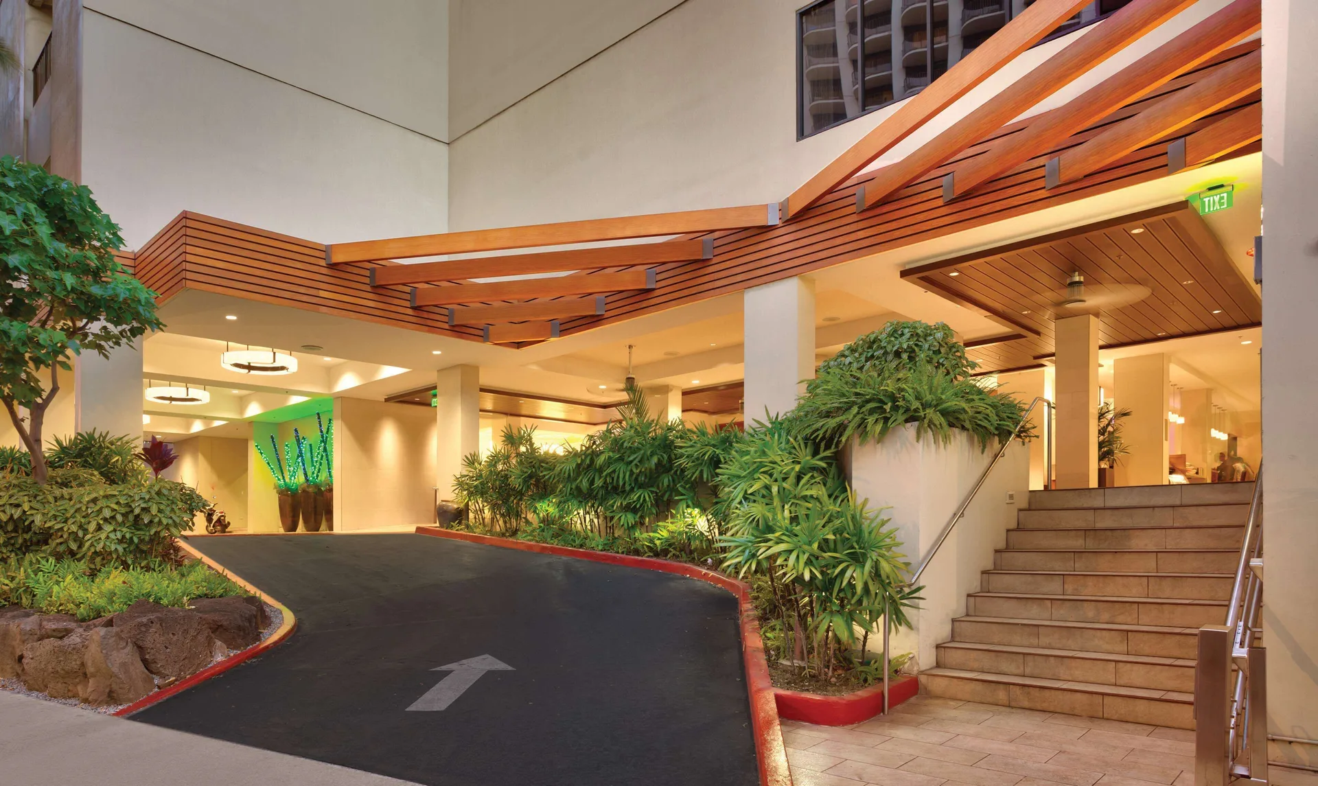 Covered driveway entrance at Hyatt Place Waikiki Beach with stairs, plants, and warm lighting.
