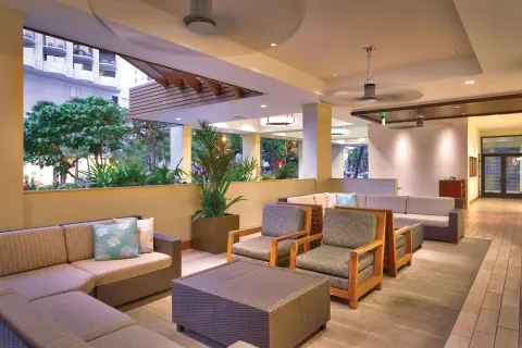 Covered lounge seating near greenery at Hyatt Place Waikiki Beach.