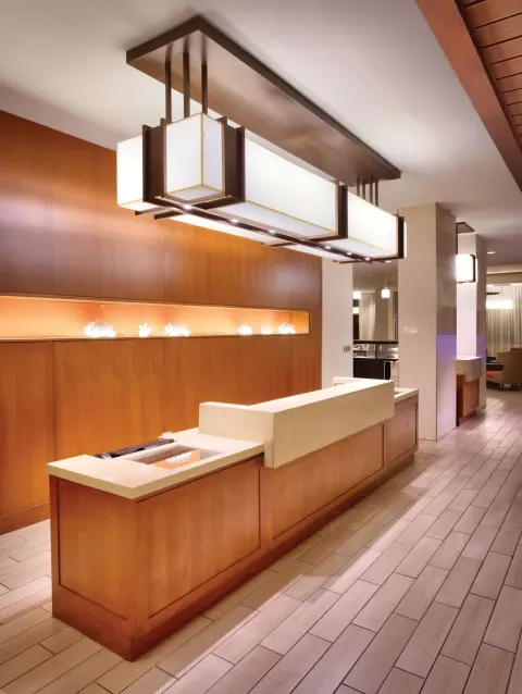Front desk with wood paneling and large pendant lights at Hyatt Place Waikiki Beach.