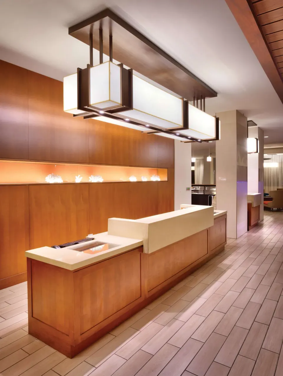 Front desk with wood paneling and large pendant lights at Hyatt Place Waikiki Beach.