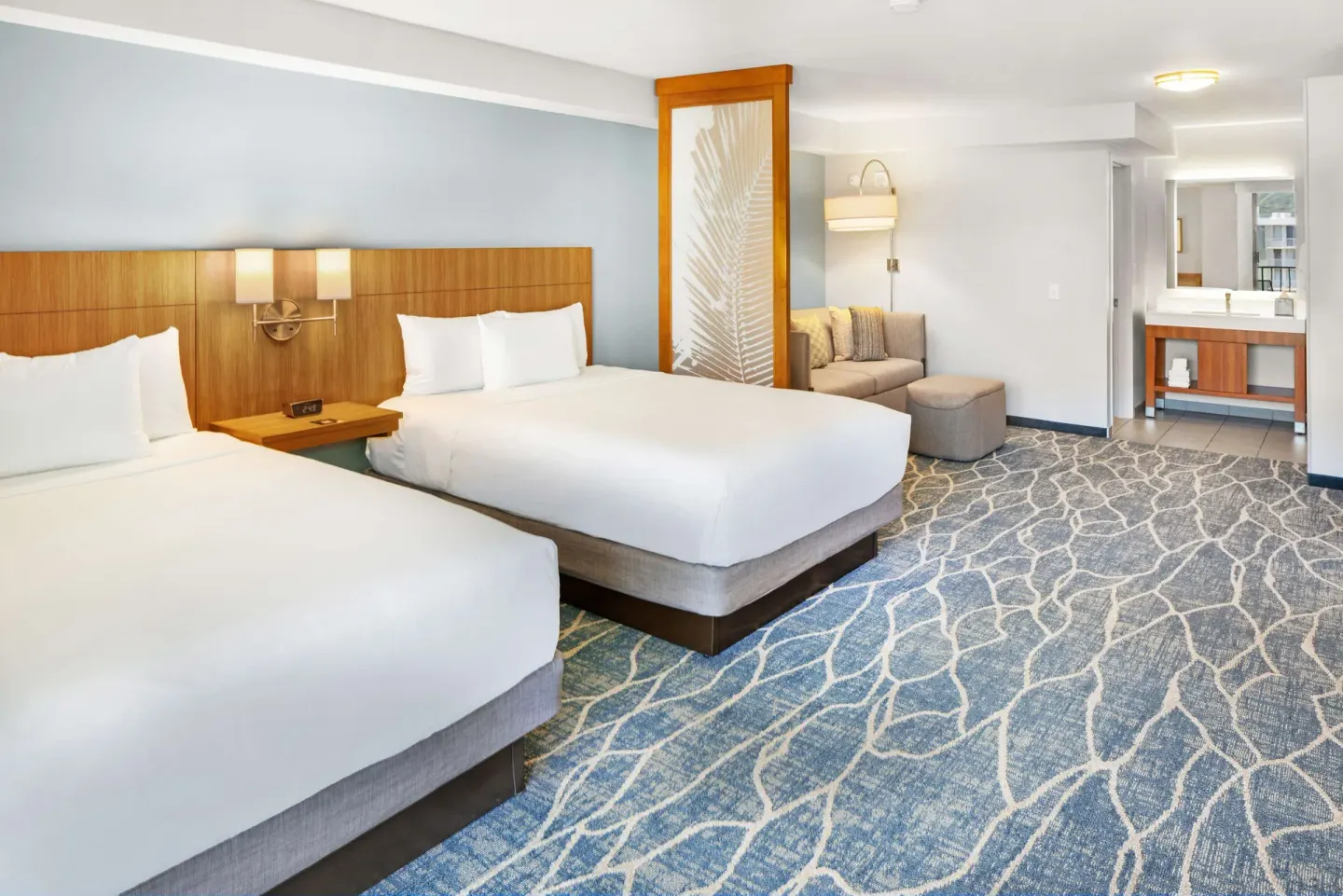 Guest room with two beds, sofa seating, and vanity area at Hyatt Place Waikiki Beach.