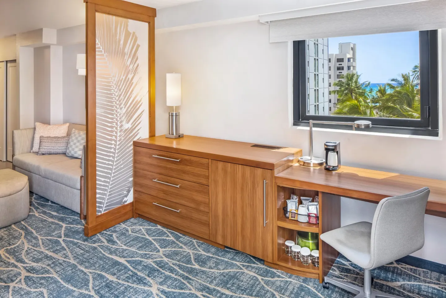 Guest room work desk and sitting area with ocean glimpse at Hyatt Place Waikiki Beach.