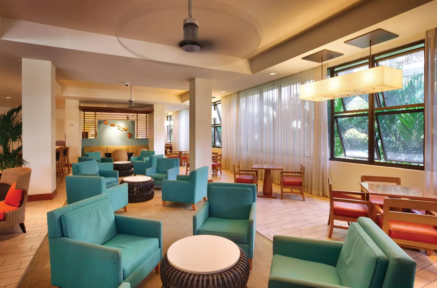 Lobby lounge with teal chairs and dining tables at Hyatt Place Waikiki Beach.