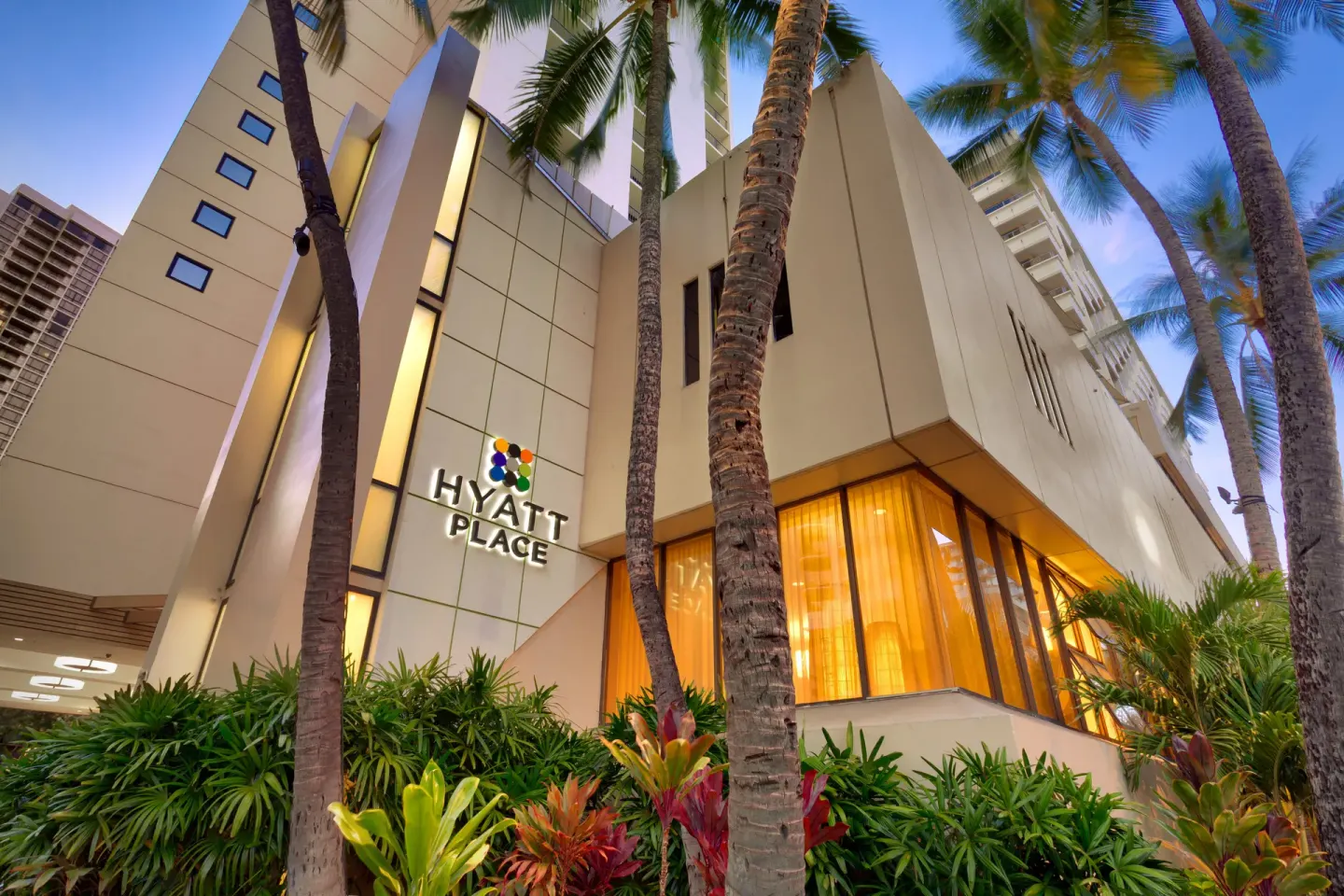 Palm-lined exterior entrance and hotel sign at Hyatt Place Waikiki Beach.