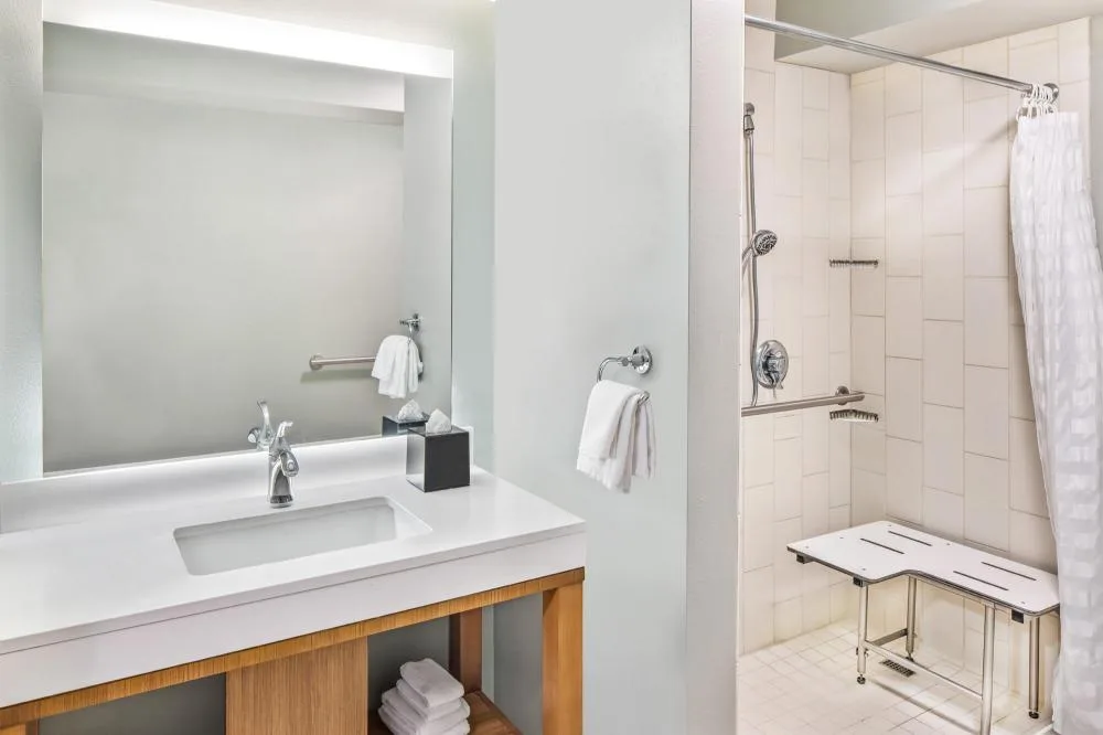 Accessible bathroom with roll-in shower and bench at Hyatt Place Waikiki Beach.