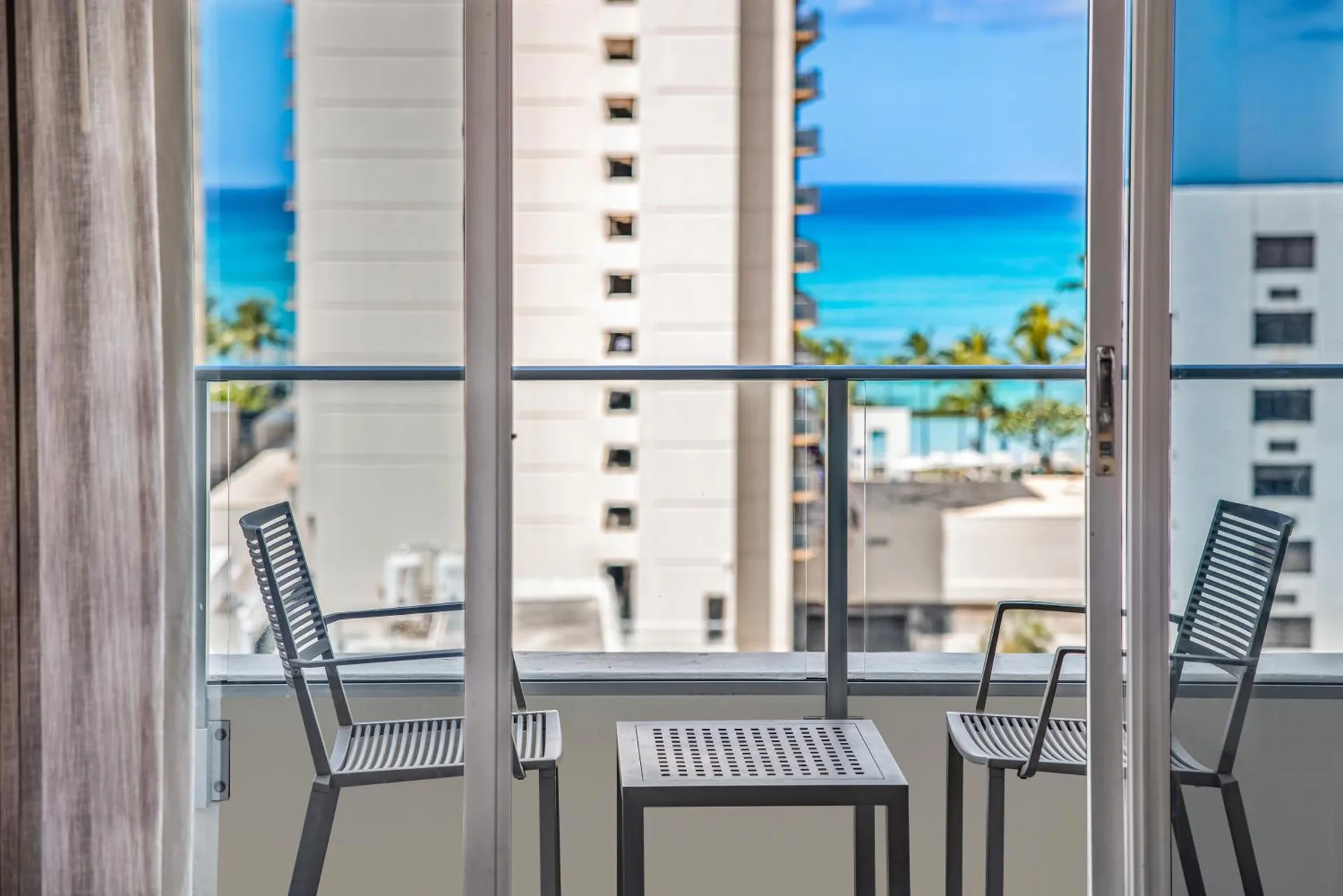 City View guest room balcony chairs with ocean between buildings at Hyatt Place Waikiki Beach.