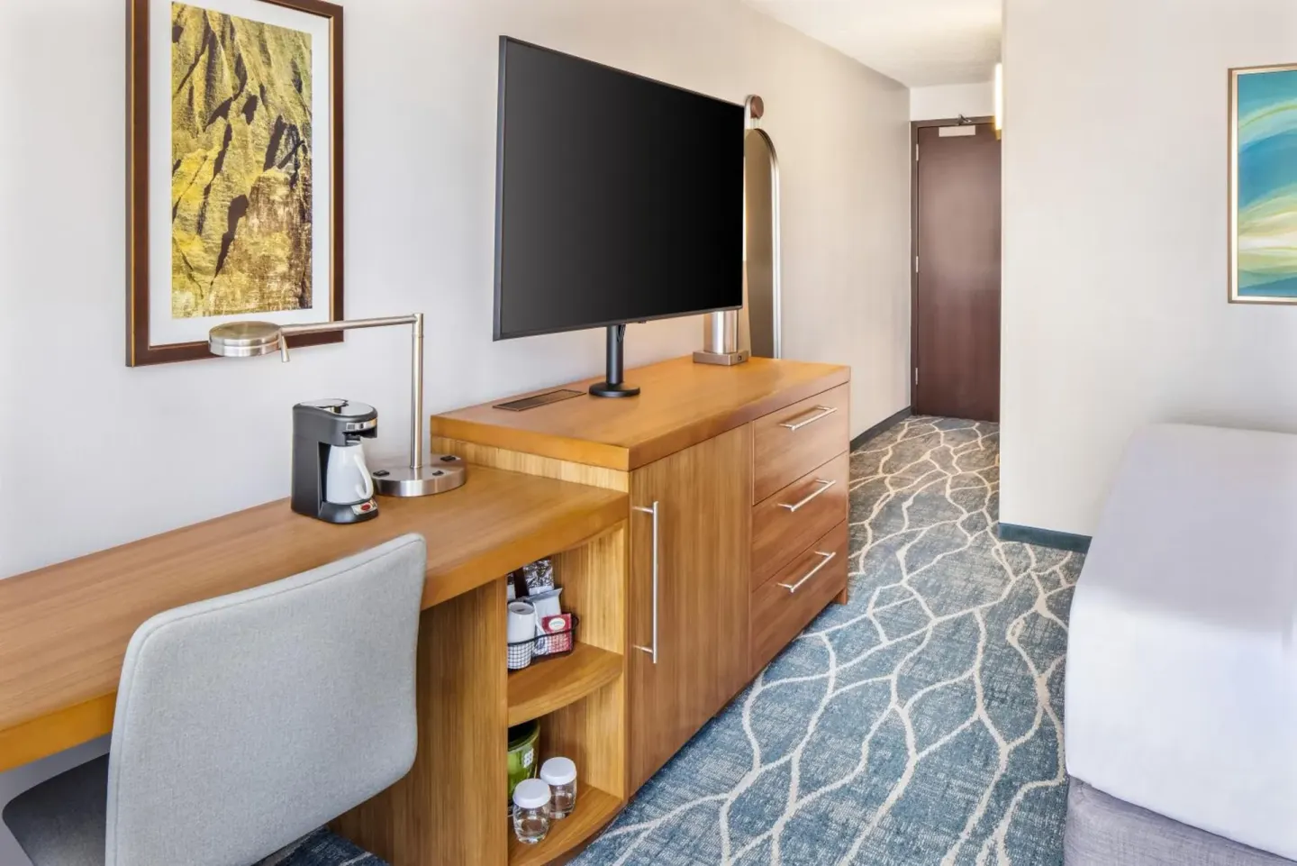 City View guest room work desk, storage, and TV by the bed at Hyatt Place Waikiki Beach.