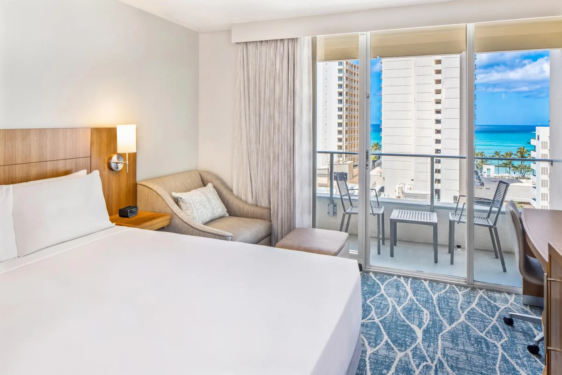 City view guest room with bed and balcony seating at Hyatt Place Waikiki Beach.