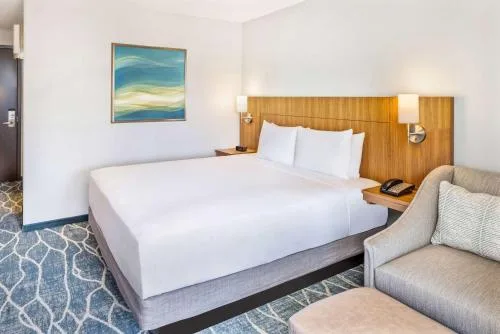 City View Deluxe room bed and sofa chair beside a wood headboard at Hyatt Place Waikiki Beach.