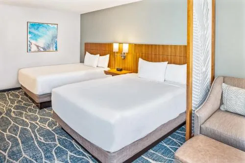 Guest room with two beds, wood headboard, and sofa bed corner at Hyatt Place Waikiki Beach.
