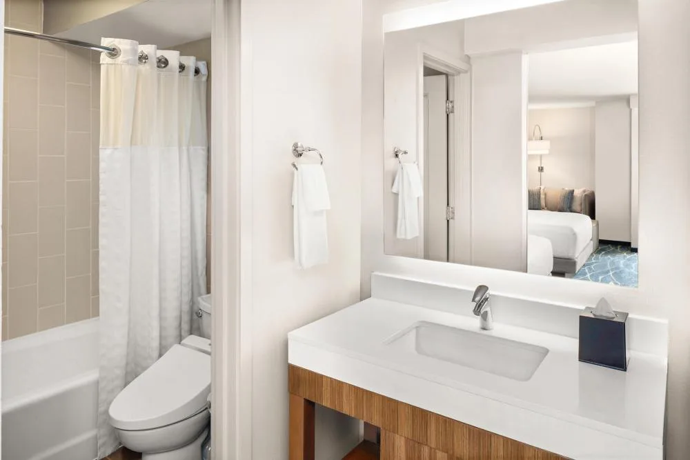 Bathroom vanity, mirror, tub, shower curtain, and toilet for a guest room at Hyatt Place Waikiki Beach.