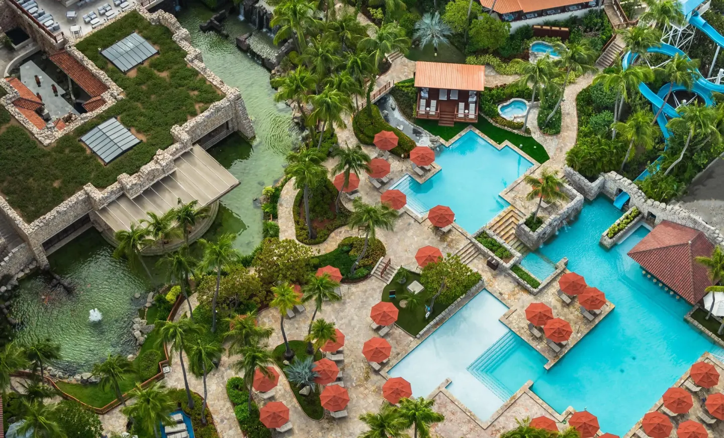 Aerial view of pools, palms, waterslide and lagoon at Hyatt Regency Aruba Resort and Casino.