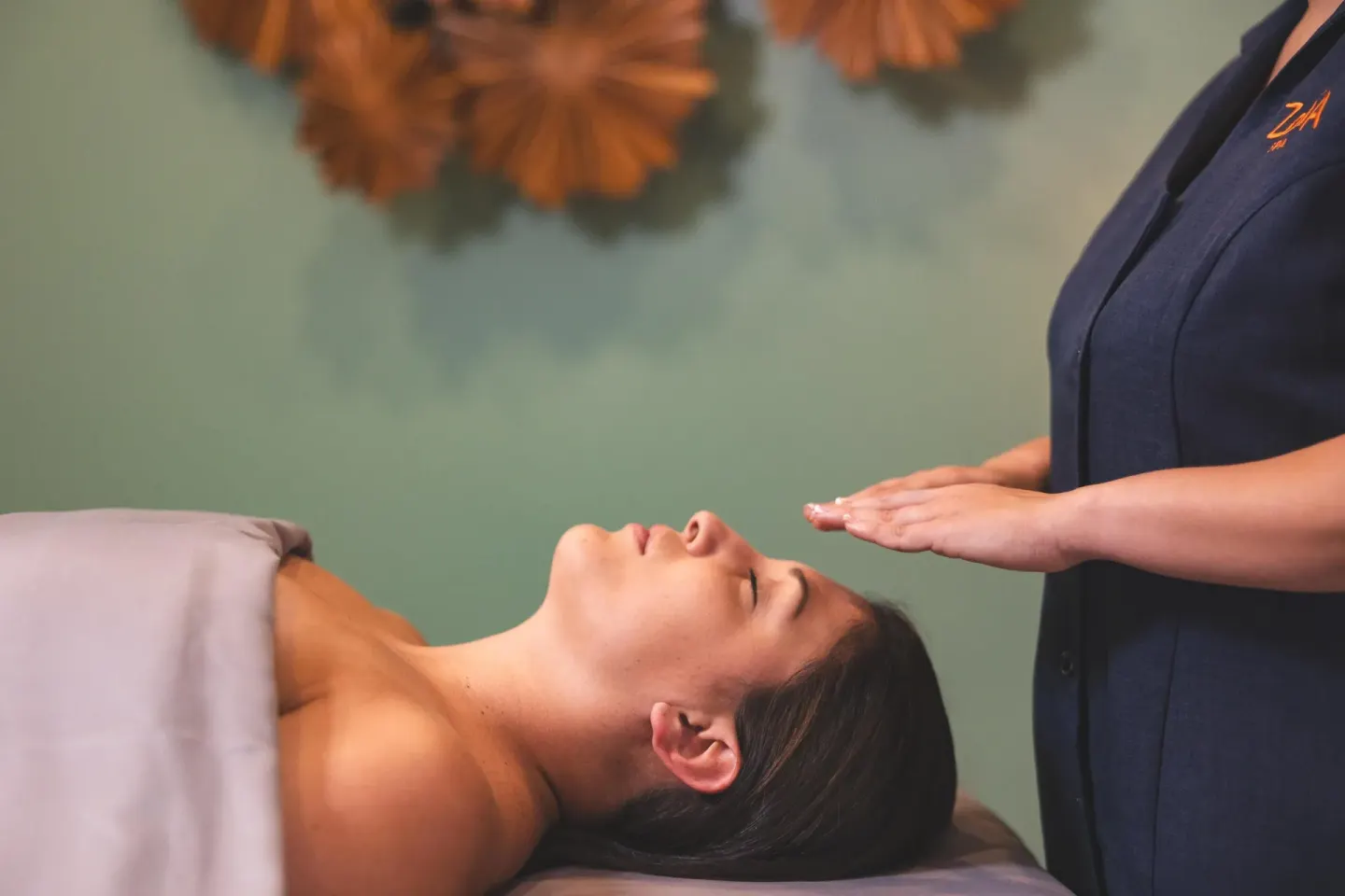 Spa treatment with a therapist holding hands above a guest at Hyatt Regency Aruba Resort and Casino.